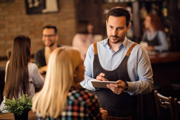 istock Waiter taking an order on touchpad while serving a guest in a bar. 1185468974