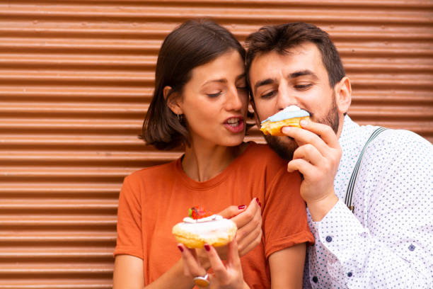 istock Man sitting with his girlfriend on street and feeding her with doughnuts. 1185469049