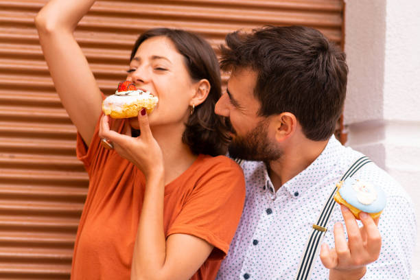 istock Couple sitting on street and eating doughnuts. 1185469080