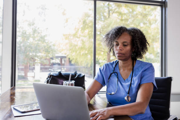уверенная медсестра с помощью ноутбука - laptop doctor using computer nurse стоковые фото и изображения