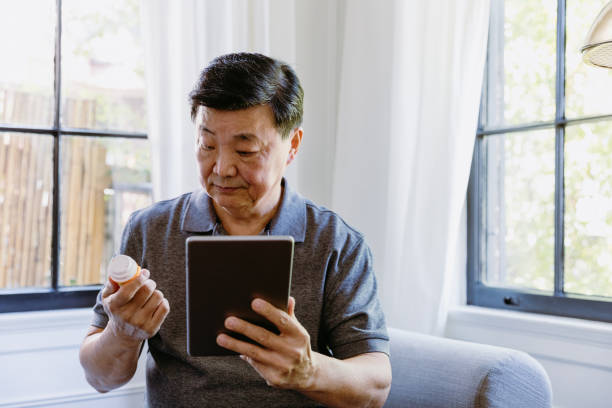 istock Senior man holding pill bottle checks label before searching internet 1185470047