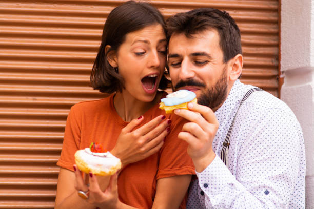 istock Man sitting with his girlfriend on street and feeding her with doughnuts. 1185472687