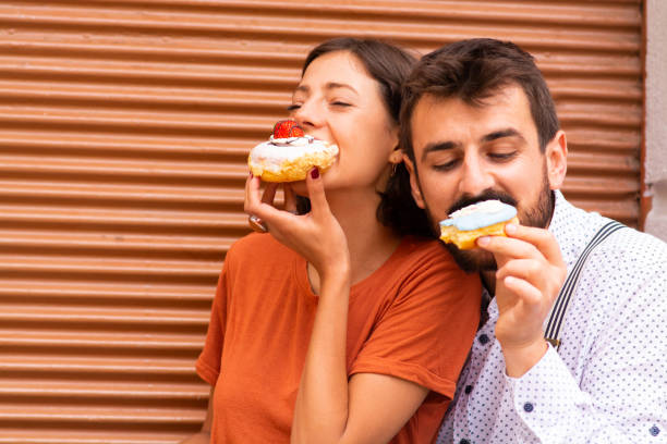 istock Couple sitting on street and eating doughnuts. 1185472689