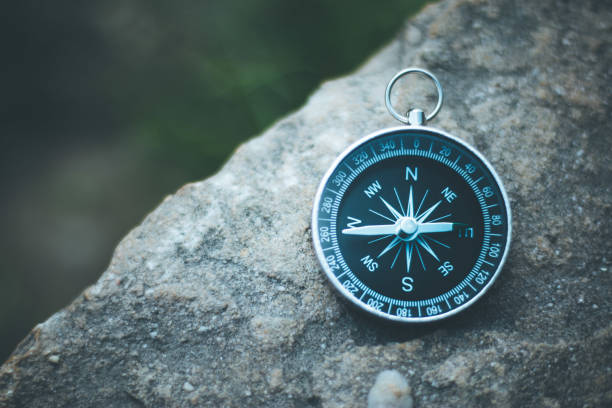 Adventure: Compass is lying on the dry floor, showing the direction Vintage compass lying on the floor. Adventure and discovery concept. Drought. west direction stock pictures, royalty-free photos & images
