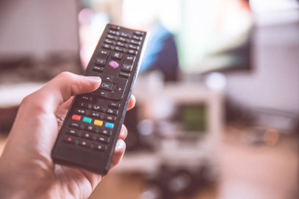 istock Male hand is holding TV remote control, smart TV. 1185475327