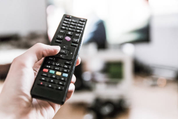 istock Male hand is holding TV remote control, smart TV. 1185475385