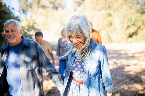 A group of senior friends led by a woman with white hair exploring outdoors.