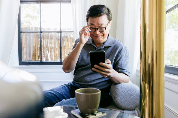 istock Senior adjusts glasses to see tablet screen clearly 1185478776