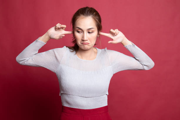 istock Young Asian woman block both ears with fingers. 1185482661