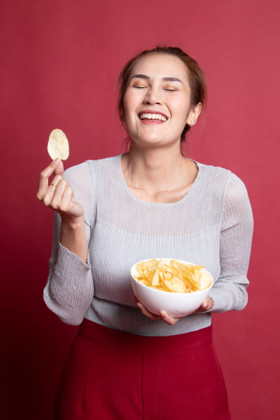 istock Young Asian woman eat potato chips. 1185483100