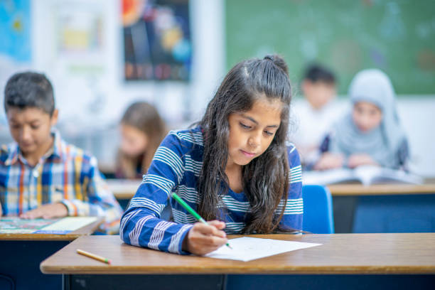 istock Hispanic Elementary School Girl Writing in Class stock photo 1185489565