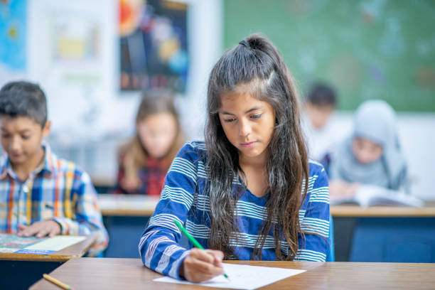 istock Hispanic Elementary School Girl Writing in Class stock photo 1185489568