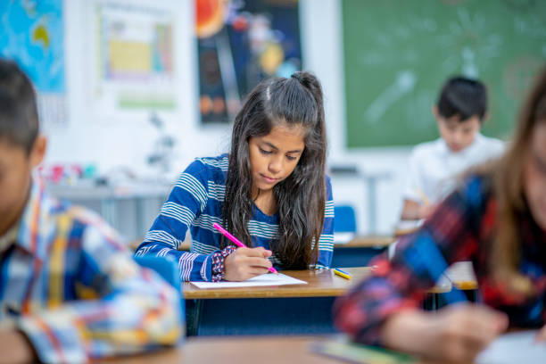 istock Hispanic Elementary School Girl Coloring in Class stock photo 1185489583
