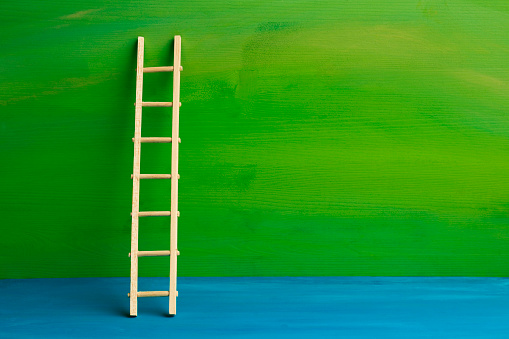 Wooden ladder on color background