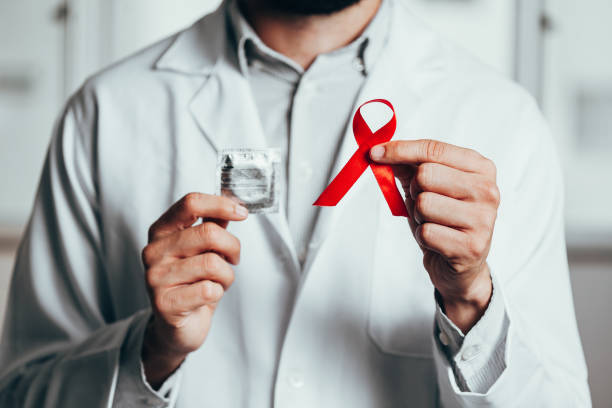 cinta roja para la concienciación sobre la enfermedad del vih en la mano del médico, 1 de diciembre, concepto del día mundial del sida. - hiv aids condom sex fotografías e imágenes de stock