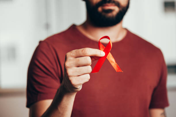 człowiek trzymający czerwoną wstążkę dla świadomości choroby hiv, 1 grudnia koncepcja światowego dnia aids. - hiv aids condom sex zdjęcia i obrazy z banku zdjęć
