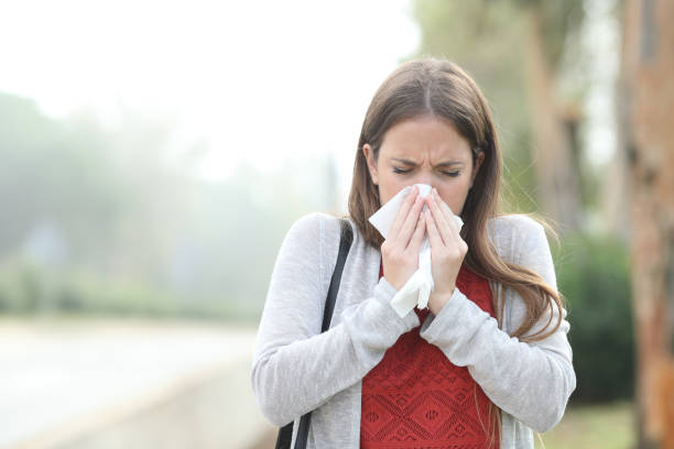 istock Ill woman blowing using tissue walking in a park with fog 1185495586