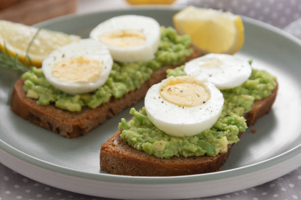 istock Avocado toast. Sandwich with egg, mashed on wholegrained bread. Healthy breakfast. 1185496146