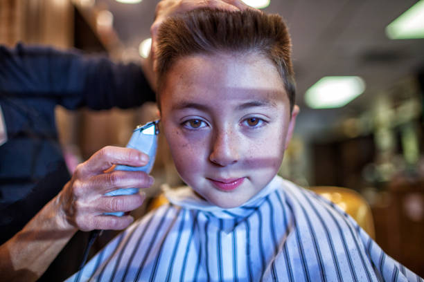 raza mixta niño caucásico asiático que lleva un delantal a rayas conseguir un corte de pelo plano de la parte superior plana con una navaja - enzo fotografías e imágenes de stock