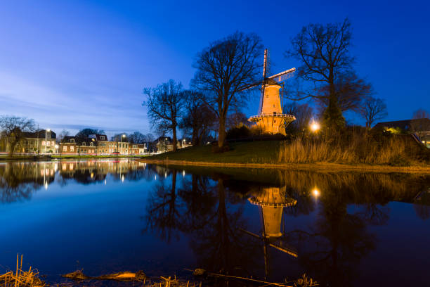 Illuminated Dutch windmill along a canal in Alkmaar, Netherlands, in evening light