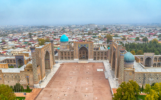 Aerial view of the world famous Registan Square in the city of Samarkand. The buildings were build from King Timur Tamerlan in the 14th century when the city of Samarkand became the capital of the Timurid Empire. The full ensemble of the Registan Square is listed as UNESCO World Heritage Site. Samarkand was one of the most important oasis and place of caravanserais at the Great Silk Road.