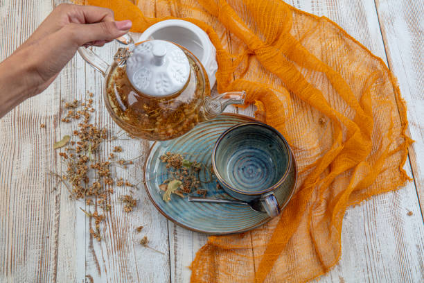 transparent glass teapot and cup with linden tea. Medicinal plant, flowers used for herbal teas, tinctures. herbal lime tree tea. close up. copy space