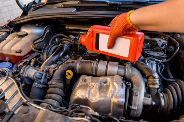 ölwechsel im autoservice. hand in schutzhandschuh mit ölflasche - nahrungsmittelzusatz stock-fotos und bilder