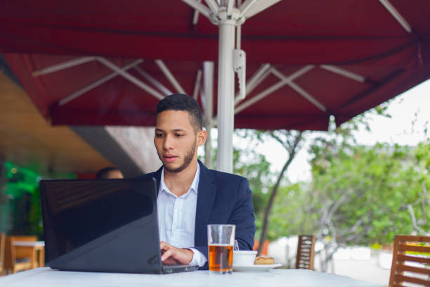 istock Latino man is sitting in restaurant while checking emails on his latop 1185505565