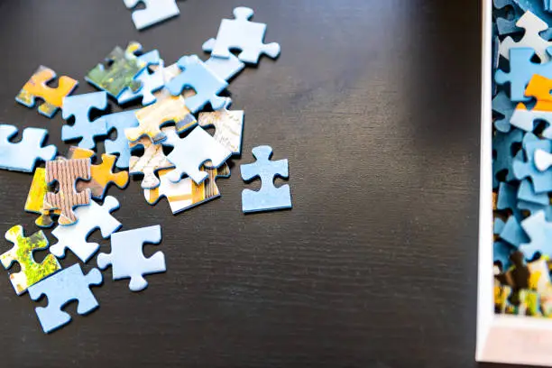 Flat top view of puzzle pieces on table scattered as game in room of house and box