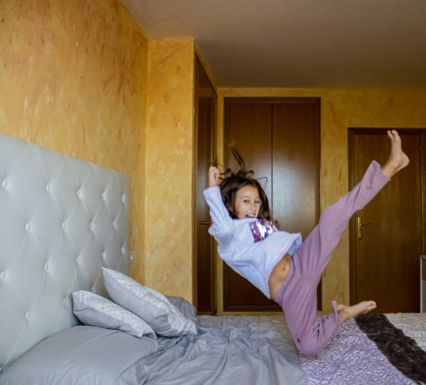 istock Little girl jumping in bed 1185509831
