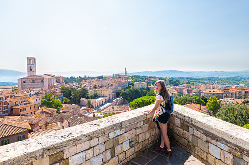 View in Perugia, Italy in Umbria cityscape of Church of San Domenico tower and rooftops of town village in summer landscape with woman at overlook