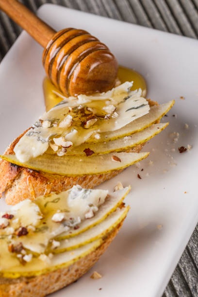 istock Appetizer bruschetta with pear, honey, walnut and blue cheese on white plate 1185511374
