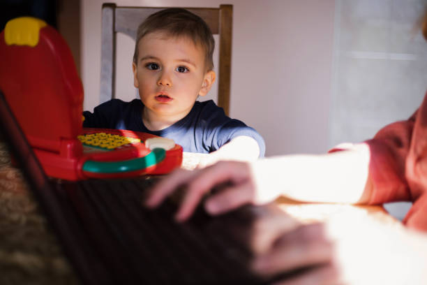 istock Toddler looking at his mother using laptop 1185530059