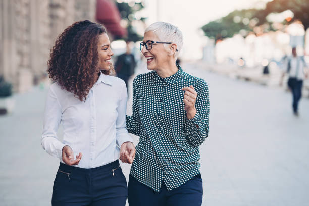 Business and friendship Two businesswomen walking together and talking mixed age range stock pictures, royalty-free photos & images