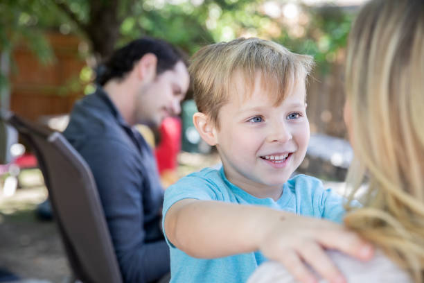 istock Cute elementary age boy smiles while talking to mother during family time in backyard 1185532763