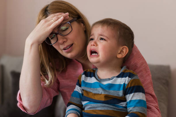 femme épuisé retenant la main sur sa tête en retenant un enfant qui n'arrête pas de pleurer - hair care photos et images de collection