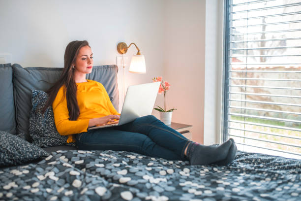 istock Beautiful woman using laptop on bed at home 1185536488