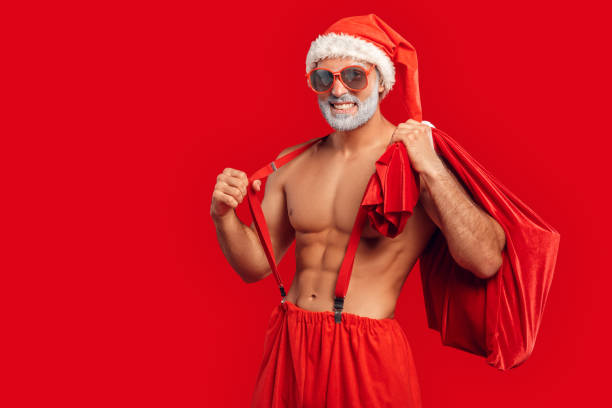 hübscher weihnachtsmann in sonnenbrille hält sack voller geschenke - sensuality men shirtless studio shot stock-fotos und bilder