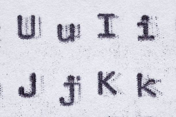 Real typewriter font alphabet with letters U, I, J, K on white paper. Macro shot