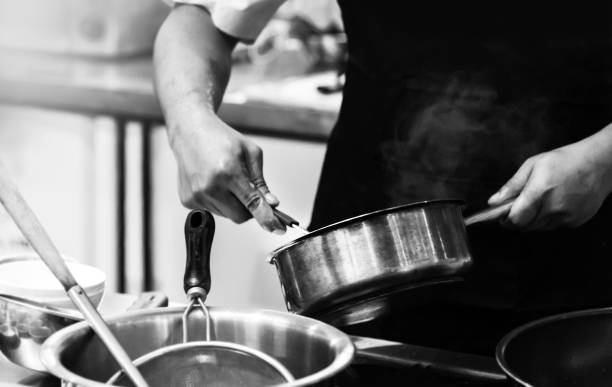 istock chef cooking in a kitchen, chef at work, Black & White background 1185561198