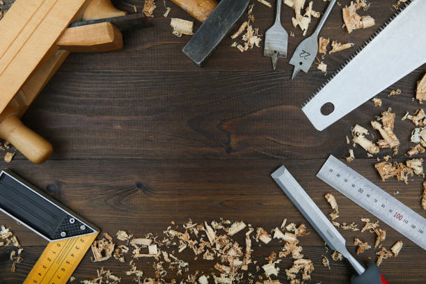 istock carpenter's background with copy space in the center. carpentry tools: planer, chisel, wood saw, square carpenter, ruler, wood drills with wood shavings on a wooden surface top view 1185570493