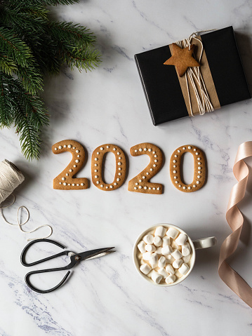 2020 new year ginger cookies and mug cacao with marshmallows on white marble background. Top view. Seasonal packaging and New Year's attributes