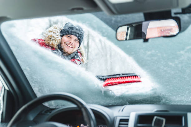istock cleaning car after snow storm smiling man with brush view from inside interior 1185577882