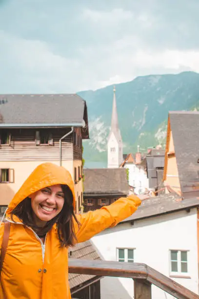 Photo of portrait of young smiling woman in yellow raincoat in hallstatt city austria
