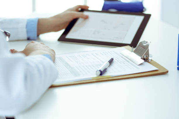 istock Doctor working table. Woman physician using tablet computer while sitting in hospital office close-up. Healthcare, insurance and medicine concept. 1185579532