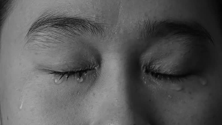 Close up eyes of woman crying with tear on black background.