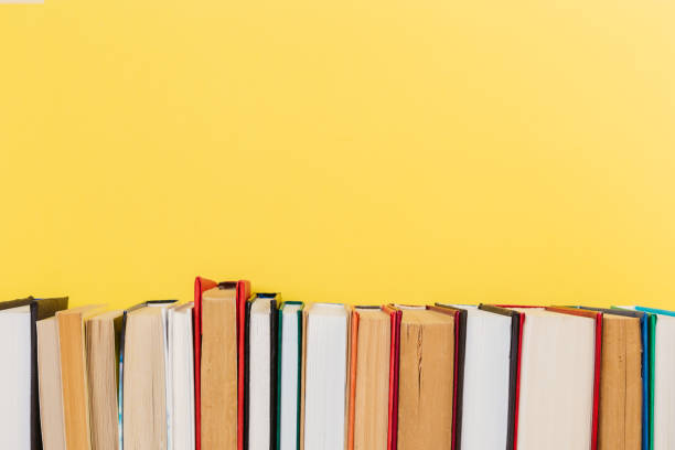 istock Simple Simple composition of many hardback books, unprocessed books on a wooden table and a yellow background. back to school. Copy space. Education. 1185582026