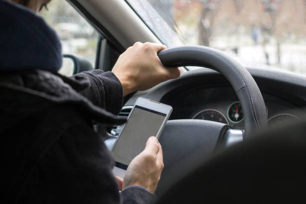 istock unrecognisable young male driver uses mobile phone while driving car 1185583764