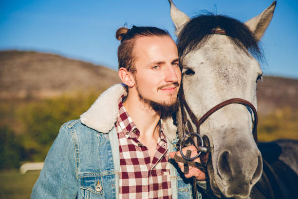 istock Man with grey horse at sunset 1185585850