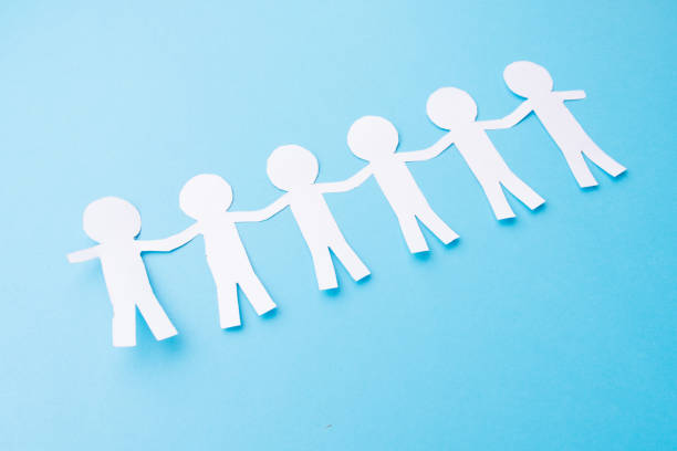 istock White paper people holding hands. Blue background 1185587751